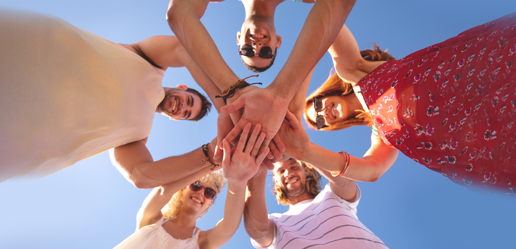 Fünf Erwachsene stehen fröhlichin einem Kreis zusammen und halten gemeinsam ihre Hände ©istock/Wavebreakmedia