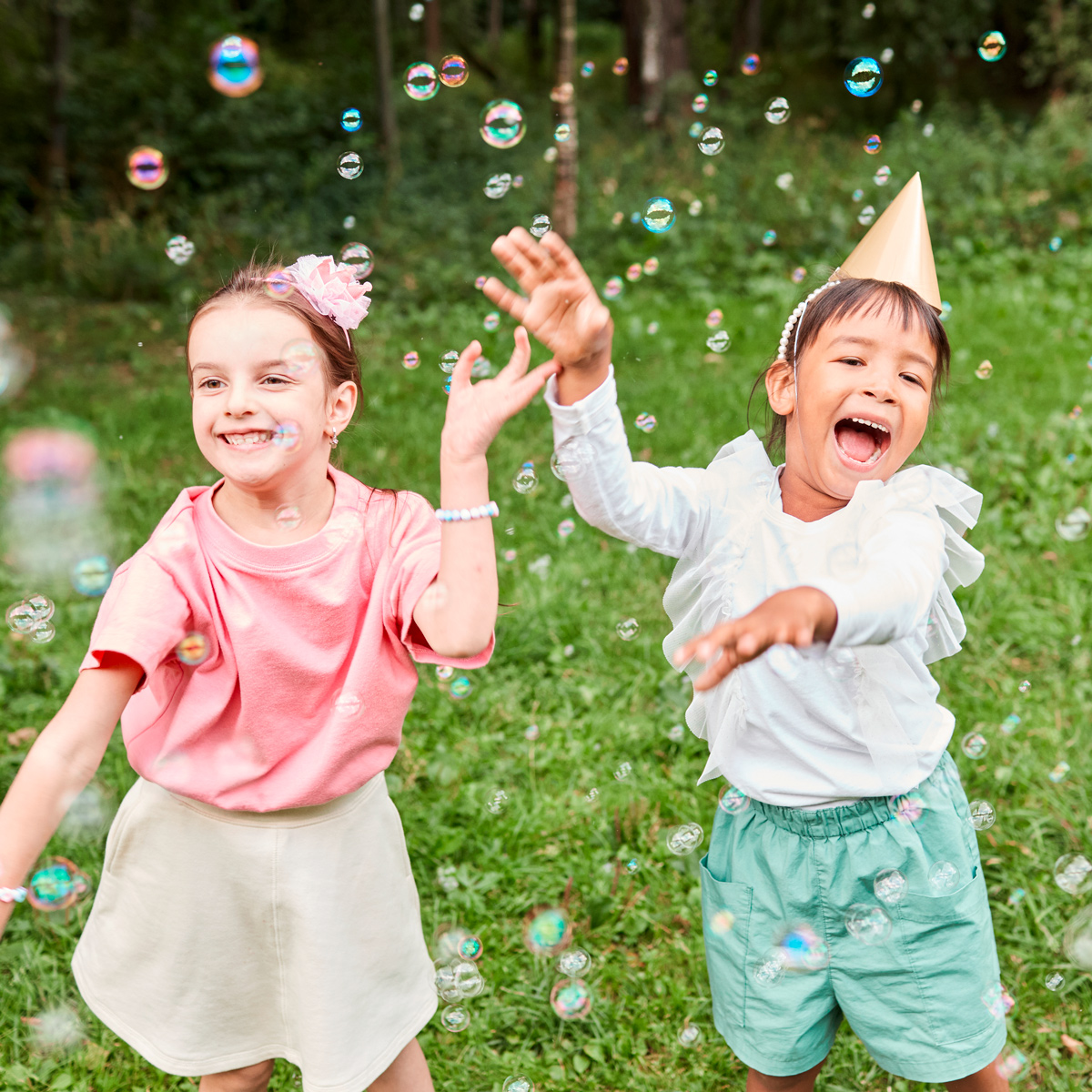 Zwei Kinder lachend mit Seifenblasen auf einer Wiese ©istock/SeventyFour